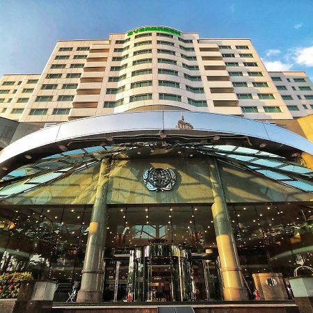 Evergreen Laurel Hotel - Taichung Bagian luar foto The photo shows the exterior of a modern hotel building. The entrance features a large, glass canopy supported by columns, creating a welcoming area. The facade of the hotel is composed of a mix of glass and concrete, with large windows that suggest 