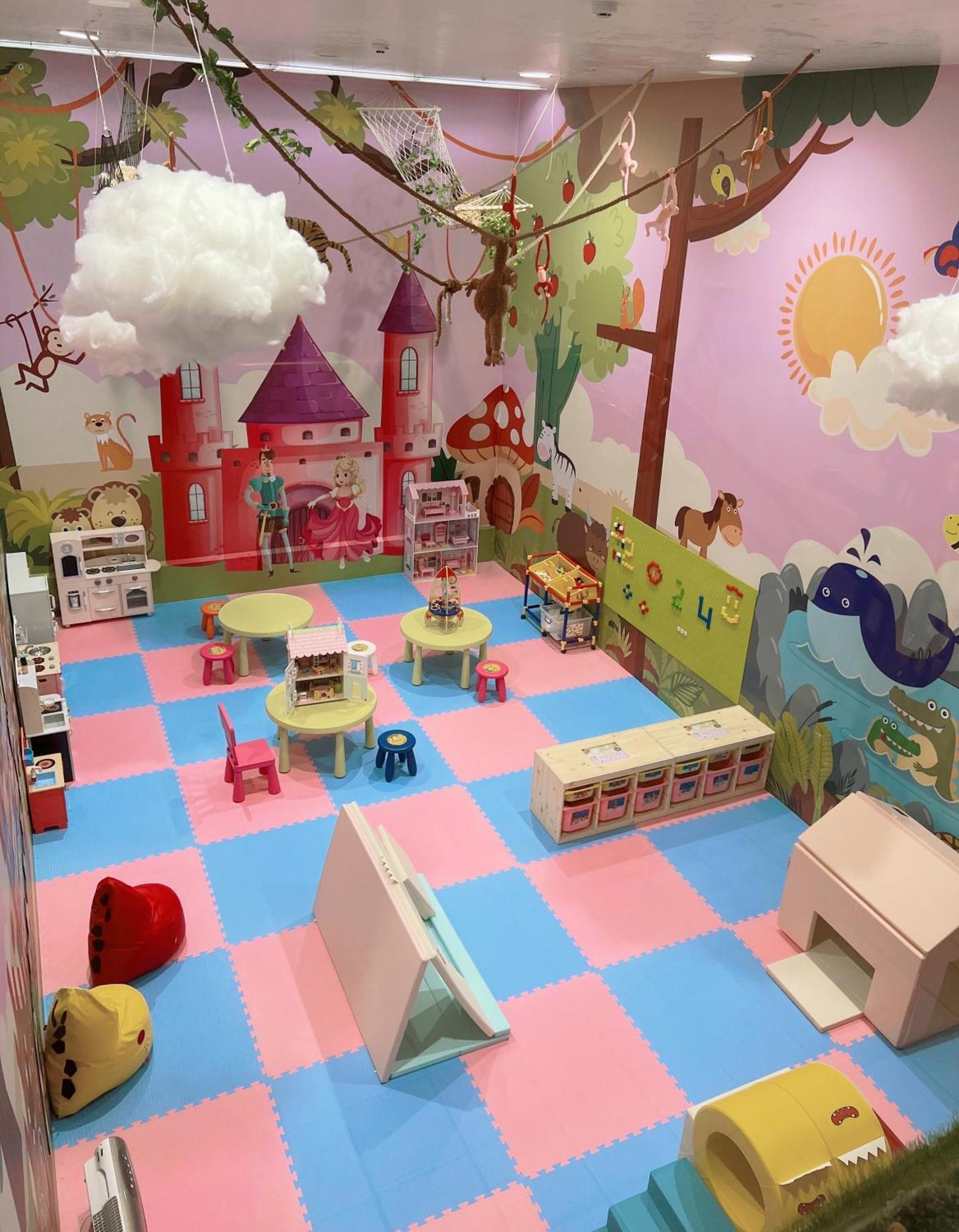 Evergreen Laurel Hotel - Taichung Bagian luar foto The photo shows a colorful playroom designed for children. It features a vibrant mural with a fairytale castle, trees, and playful animals on the walls. The floor is covered with interlocking foam tiles in pink and blue, providing a soft play surface
