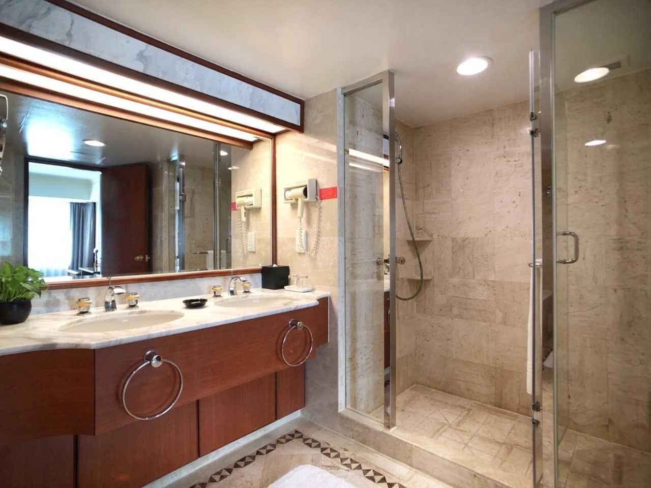 Evergreen Laurel Hotel - Taichung Bagian luar foto The photo depicts a modern bathroom featuring a double vanity sink with a marble countertop and wooden cabinetry. Above the sinks, there is a large mirror with integrated lighting. To one side, there is a shower enclosed in glass, showcasing a sleek 