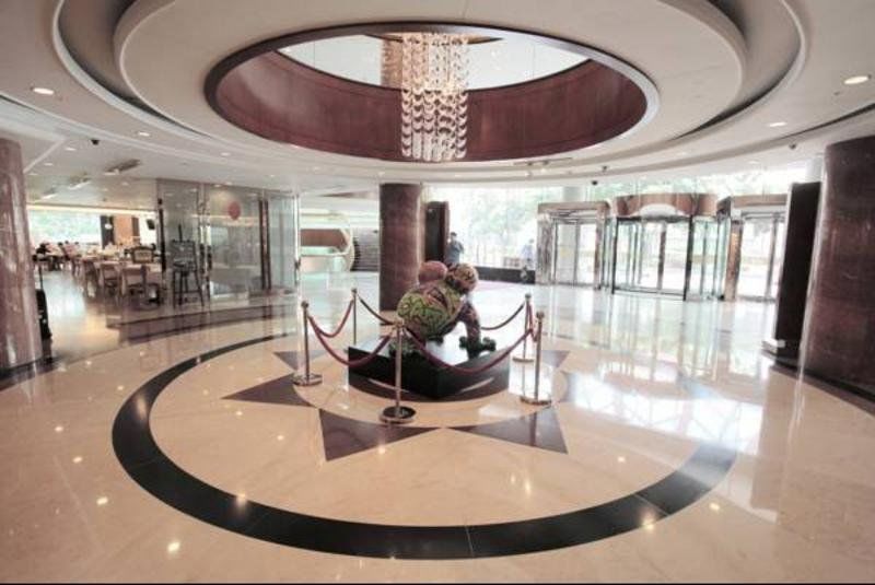 Evergreen Laurel Hotel - Taichung Bagian luar foto The photo depicts an elegant indoor space, likely the lobby of a hotel or a building. The flooring is made of polished marble tiles, featuring a circular design with contrasting black and light-colored sections. At the center, there is a sculpture su