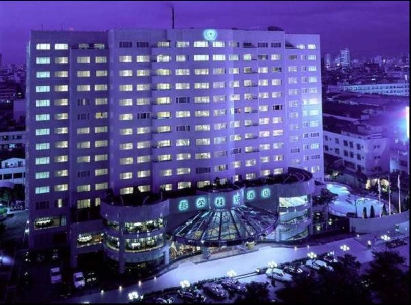 Evergreen Laurel Hotel - Taichung Bagian luar foto The photo shows a large hotel building illuminated in a purple hue during the evening or nighttime. The facade features numerous windows, many of which are lit, suggesting occupancy. The entrance area appears modern and curved, with a design that inc