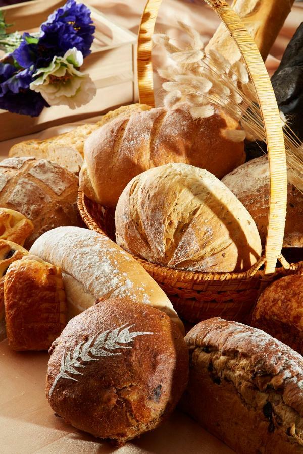 Evergreen Laurel Hotel - Taichung Bagian luar foto The photo shows a variety of freshly baked bread arranged in a woven basket. There are different types of bread, including round loaves, baguettes, and crusty rolls, showcasing a range of colors and textures. Some loaves have distinctive patterns or 