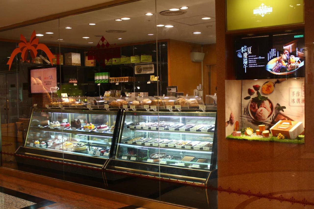Evergreen Laurel Hotel - Taichung Bagian luar foto The photo shows a display case in a bakery or dessert shop. The glass case is filled with a variety of pastries, cakes, and desserts arranged neatly. Behind the display, there is a counter with additional items and desserts visible. The walls are dec