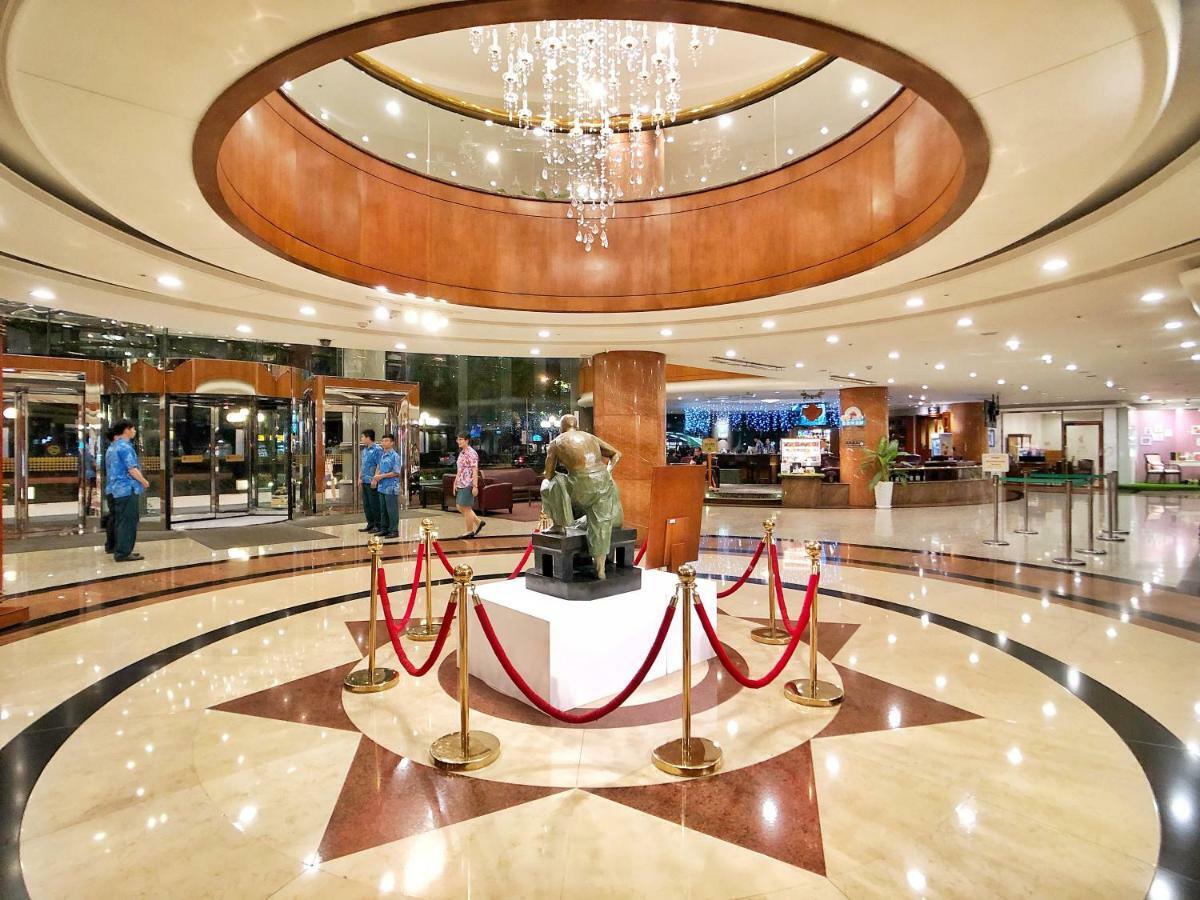 Evergreen Laurel Hotel - Taichung Bagian luar foto The image shows a spacious lobby area of a building, likely a hotel or an upscale establishment. The design features a circular ceiling with a chandelier hanging from it, creating a bright and elegant ambiance. At the center, there is a statue, likel