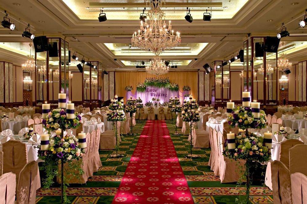 Evergreen Laurel Hotel - Taichung Bagian luar foto The photo shows an elegantly decorated banquet hall set up for a wedding or formal event. The center aisle is lined with rows of elegantly draped chairs and features a bright red carpet. On either side of the aisle, there are beautifully arranged flo