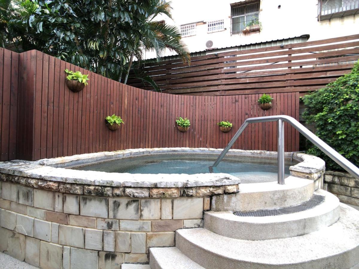 Evergreen Laurel Hotel - Taichung Bagian luar foto The photo shows a small outdoor hot tub or spa area. It's surrounded by a wooden fence, with several planters containing greenery attached to the wall. The hot tub is round, with a stone border, and there are steps leading up to it with a stainless s