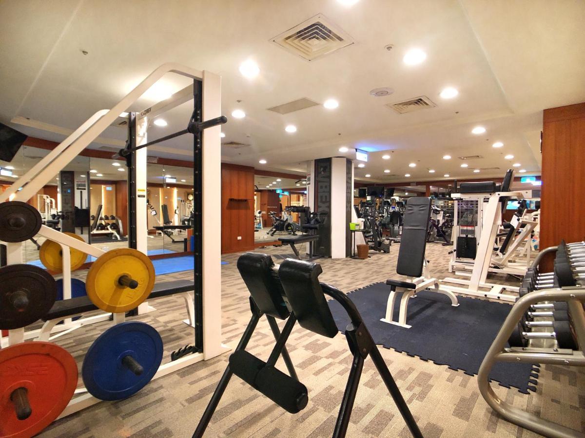 Evergreen Laurel Hotel - Taichung Bagian luar foto The photo shows a gym interior with various workout equipment. On the left, there are weights of different colors stacked on a weight rack. In the foreground, there's a bench for exercises, and in the background, multiple machines for strength traini
